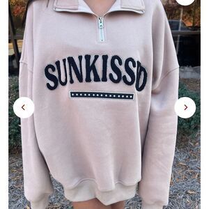 Sunkissed Coconut tan quarter zip sweater with brand in black writing‎